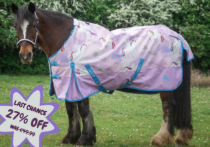 A dark brown horse standing on grass outdoors wearing a lavender-purple turnout blanket with a white unicorn and rainbow print and bright blue trim. A purple sale badge in the lower left reads 'LAST CHANCE 27% OFF WAS £49.